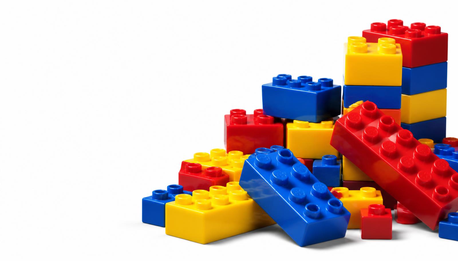 A pile of red, yellow and blue LEGO bricks on a white background